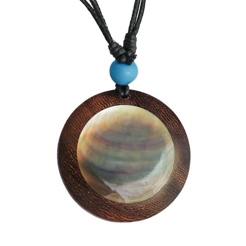 The Holzkette Perlmutt features a round Holzanhänger with glossy Muschel Inlay, a textured brown ring, and a blue bead on an adjustable black Baumwollkordel—perfect as a unisex Black Shell necklace.