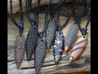 Load image into Gallery viewer, Seven carved wooden pendants with intricate, nature-inspired patterns hang from black cords on rustic wood—each one a unique Surferkette Holz Halskette Gravur Baumwolle verstellbar, perfect as a friendship necklace or surf style accessory.
