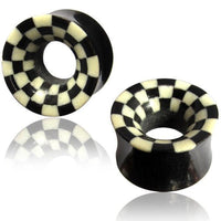 Load image into Gallery viewer, Two black Horn Flesh Tunnel Schachbrett schwarz weiß plugs with flared ends and a checkered rim design are shown on a white background, featuring reflections beneath them.
