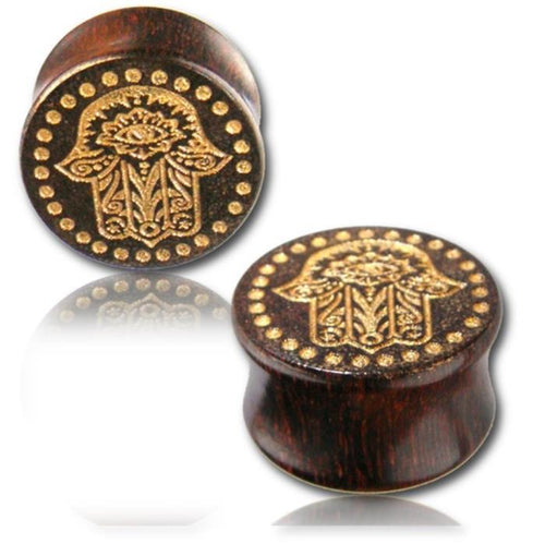 Two dark Holz Plug Poor Mans Hand Tamarind Khamsa plugs with gold-painted, laser-engraved Fatima eye and dotted tribal design, displayed on a reflective surface against a white background.