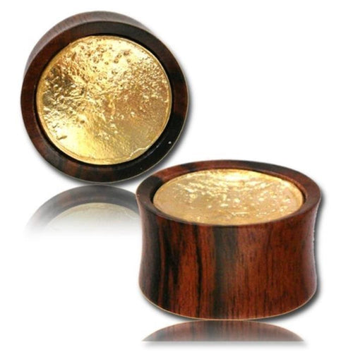 Two Holz Plug two tone Arang Wood Brass Inlay tunnels, featuring flared edges and an antique golden tribal design, are shown on a white background—one lying flat and the other upright to display both polished surfaces.