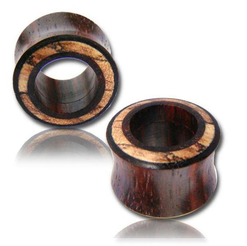 Two round Tamarinden Holz Flesh Tunnel Plugs in brown and light tones are shown, one upright and one lying down. These organic Ohrschmuck pieces rest on a white surface with a faint reflection beneath.