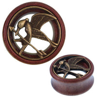 Load image into Gallery viewer, A round Holz Tunnel Schwalbe Pfeil Schnabel Plug features an antique golden finish, tribal design, and elegant brass inlay inspired by the Hunger Games, with a bird holding an arrow in its beak.
