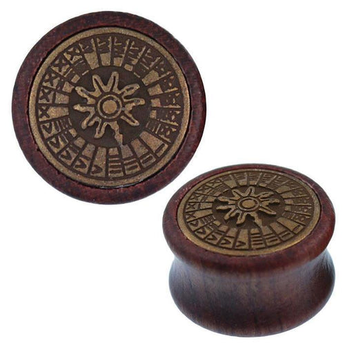 A pair of Holz Plug Sonnenuhr oxidiert with antique golden brass inlay, featuring a carved circular sun symbol and geometric patterns inspired by tribal tunnel expander style.