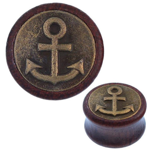 The Holz Plug Anker oxidiert features an antique golden brass inlay with a tribal tunnel expander design. Its round shape displays a raised anchor emblem and circular border, shown in close-up and full views.