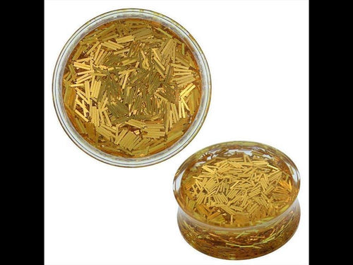 A round, clear container filled with thin metallic gold strips—similar to Plug gold Glitzer Streifen Acryl transparent Tunnel Expander Piercing Ohrschmuck—shown from a top and angled side view against a white background.