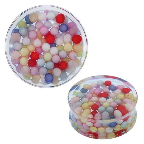 A round, transparent Acryl Plug Tunnel Expander Piercing Ohrschmuck, filled with bunte Kügelchen in pastel tones. Side view highlights the clear container and the layered arrangement of beads inside.