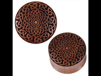 Load image into Gallery viewer, The Plug Celtic Sawoholz Holz braun Geflochten Lasergravur is a round wood plug with a removable lid, showcasing an intricate Celtic braided design and a detailed floral motif, laser-engraved on the top and sides.

