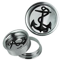Load image into Gallery viewer, The Schraub Plug Tunnel silbern schwarz Edelstahl Anker Seil Piercing includes two round silver plugs with black anchor designs—one stands upright, while the other lies flat with its threaded back detached and placed beside it.
