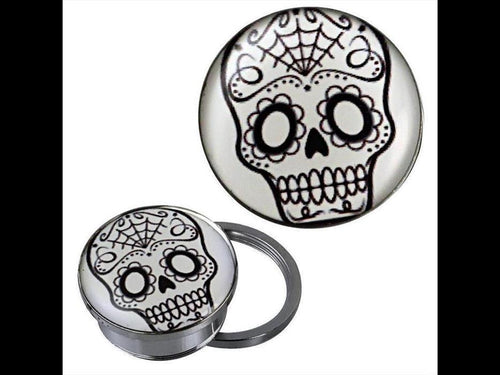 A silvery stainless steel screw plug tunnel piercing with a black and white Candy Skull acrylic design, featuring floral eye patterns and a spiderweb on the forehead, inspired by Skull Motiv art.