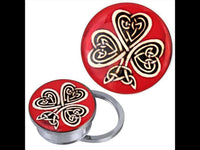 Load image into Gallery viewer, The Schraub Plug Tunnel silbern Edelstahl keltische Knoten Kleeblatt rot Acryl Piercing is a round metal phone grip with a red top, gold Kleeblatt motif, and Celtic knot design. Shown from top and side angles.

