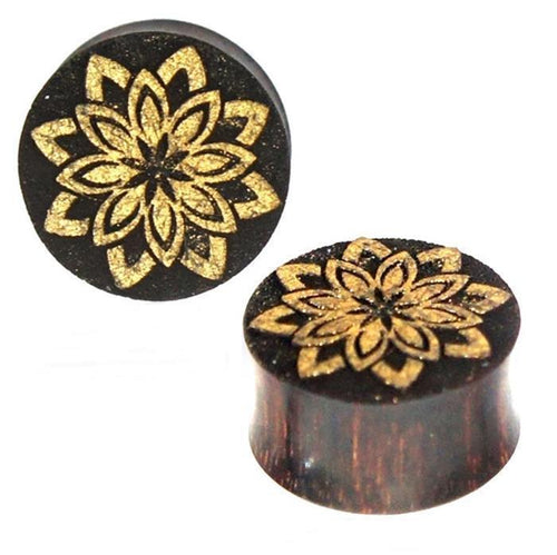 Two round, dark brown Tamarinde wood plugs with a golden engraved floral design. One Plug Holz dunkelbraun Holz Tamarinde Maserung Gravur golden Blume spitz Piercing is shown from the front, the other at an angle.
