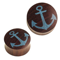 Load image into Gallery viewer, Two round, dark brown Holz Plug Anker ear plugs with crushed turquoise stone inlay and blue anchor designs are displayed on a white background.

