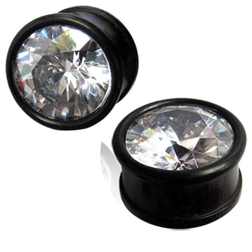 A pair of hand-carved Kristallplug Eisenholz schwarz Holzplugs with large, round, clear rhinestone fronts that sparkle and reflect light.