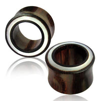 Load image into Gallery viewer, Two cylindrical Holz Flesh Tunnel Perlmutt Inlay weiß Plugs in dark brown with a white and black ring detail, displayed on a white background with a subtle reflection underneath.
