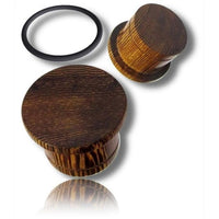 Cargar imagen en el visor de la galería, Two Flat Top Plug Siamea Holz single flared tunnels with maserung (grain pattern) are shown—one upright, one on its side—beside a black Gummiring (rubber ring) on a white background, all casting soft shadows.
