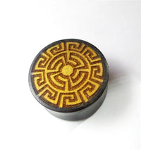 Load image into Gallery viewer, The Plug Tamarindenholz griechisch Sonne Ornament Spiralen Inlay double flared flach is a round plug made from Tamarind wood, featuring a dark finish and a yellow-brown geometric sun spiral inlay with a central circle and symmetrical design.
