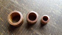 Load image into Gallery viewer, Three Flesh Tunnel Teakholz Sawoholz Rim rot double flared rings, each a different size, are lined up on a textured brown wooden surface. Their smooth, rounded edges and red inner rims evoke expert craftsmanship.
