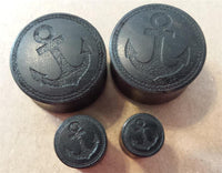 Load image into Gallery viewer, Four black Flesh Plug Ebenholz Anker Seil Ring double flared Lobe Dehner with engraved anchor designs are displayed on a light surface, showcasing various sizes and featuring detailed schwarz Gravur.
