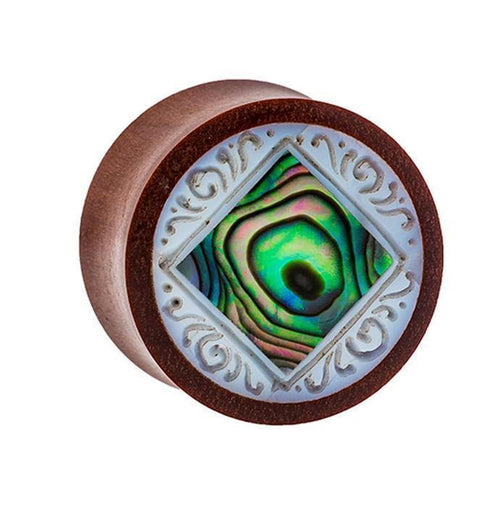 The Organic Sabaholz Plug features a rounded design with a diamond-shaped Paua Abalone Perlmutt inlay and detailed white tribal engravings, inspired by the "Paua Abalone eckig gerahmt Perlmutt Tunnel Tribal Expander.