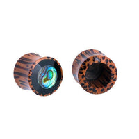 Load image into Gallery viewer, Two "Holz Plug Tunnel Kokosholz" ear gauges are shown on a white background: one features a shimmering Paua Abalone resin inlay with tribal circles, while the other reveals its hollow Kokosholz interior.
