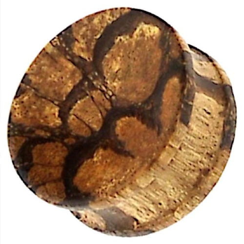 A close-up view of the Tribal Tigerholz konkav Maserung Holz Plug, a hand-carved brown ribbed wood plug with unique grain patterns resembling tree rings or natural textures.
