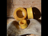 Load image into Gallery viewer, Three "Jackfrucht Holz Tunnel ocker Pünktchen konvex dick" flesh tunnels of varying sizes rest on a textured wooden surface, sunlight casting shadows. The tunnels showcase natural wood grain and a warm ochre hue with dotted details.
