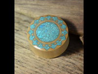 Load image into Gallery viewer, A double flared Plug Krokodilholz with a crushed Türkis Sonne inlay, featuring a decorative circular pattern and light wood tones, displayed on a rustic wooden surface.
