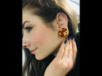 Load image into Gallery viewer, A woman with long brown hair and a nose piercing shows off a Flesh Plug Weltkarte Holz Welt Erde Globus double flared, holding her hand near her ear and smiling at the unique engraved wooden world map design.
