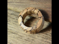 Load image into Gallery viewer, A Bananenholz Flesh Tunnel hell ribbed straight konvex with a natural grain and smooth finish lies on a textured wood surface—perfect for those who value unique Holztunnel jewelry.
