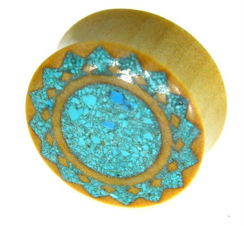The Plug Krokodilholz crushed Türkis Sonne double flared is a round wood plug with a geometric sunburst pattern of crushed turquoise inlay on one end, set against a white background.