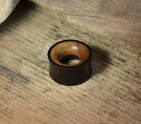 Load image into Gallery viewer, A handmade Holz Tunnel in schwarz-braun Eisenholz and Teakholz, with a dark exterior and lighter inner surface, sits on a textured wooden surface.
