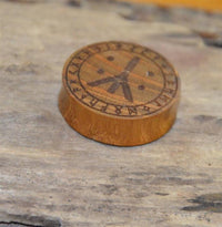 Load image into Gallery viewer, A round Holz Plug Teakholz Rune Leben Tod Punkte double flared with carved runes and a compass-like design sits on a rustic wooden surface.
