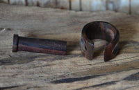 Load image into Gallery viewer, A Plug Narraholz Pin-Creole braun gemasert Holz-Pin Creole rests on a rustic wooden surface, showing its dark wood color and open gap design.
