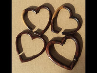 Load image into Gallery viewer, Four Piercing Narraholz Holz Expander dunkelbraun Herz Dehner key rings are arranged on a light brown surface, each showcasing unique handcrafted wood grain—perfect for fans of artisanal design.
