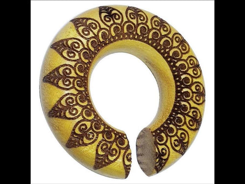 A round, gold-toned African neck ring with a small opening, adorned with intricate brown spiral and geometric designs like those found in the Pfau Mandala Jackfrucht Holz Ohr Donut Piercing.