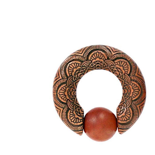The Captive Bead Klemmkugel Ring Sawoholz Piercing Mandala is a round metal ornament with intricate floral engravings and an open circle design, featuring a Sawoholz expander bead between the open ends at the bottom.
