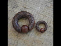 Load image into Gallery viewer, Two Captive Bead Klemmkugel Ring Sawoholz Piercing Mandala earrings with intricate mandala patterns and round wooden beads are displayed on a textured wooden surface.

