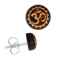 Load image into Gallery viewer, The Holzohrstecker Edelstahl Sonoholz rund 8mm features a dark brown front with a gold Om symbol and decorative gold border, plus a metallic post and back.
