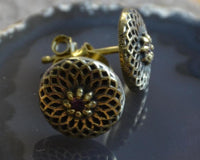 Load image into Gallery viewer, A close-up of Messing Stein Ohrstecker antik gold Dahlie 10mm, featuring an intricate, flower-inspired filigree pattern in gold metal, displayed on a glossy dark surface.
