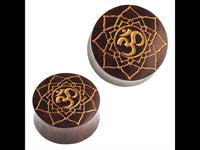 Load image into Gallery viewer, Two round, dark brown "Holz Plug Sternblume OM" Sonoholz plugs with golden mandala and Om engravings are displayed against a white background.
