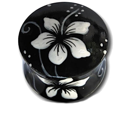The Holz Plug Hawaii Blume weiß schwarz Teakholz handbemalt is a small, round black plug with a lid, featuring a hand-painted white flower design—ideal as unique jewelry or to pair with your Hibiskus Piercing.