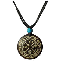 Load image into Gallery viewer, The "Halskette Holz Türkis verstellbar Anhänger gold silber" features a round dark wood pendant with a golden Norse runic design and knot border on an adjustable cotton cord, accented by a small turquoise bead above the pendant.
