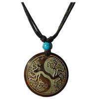 Load image into Gallery viewer, The Halskette Holz Türkis verstellbar Anhänger gold silber features a round wood pendant with a yin-yang tree design, adjustable cotton cord, and a small turquoise bead above the pendant.
