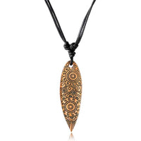 Load image into Gallery viewer, The Surferkette Holz Halskette Gravur Baumwolle verstellbar features an elongated, leaf-shaped wooden pendant engraved with circular geometric patterns on a black, adjustable cotton cord.
