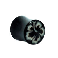 Load image into Gallery viewer, The Horn Plug schwarz Bone Inlay Hawaii Blume features a black cylindrical design with a white hibiscus flower, ideal as a stylish tribal piercing, organic expander, or decorative Ohrstecker.
