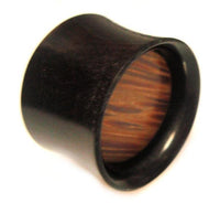 Load image into Gallery viewer, The Horn Plug Flesh Tunnel Büffelhorn Palm Holz features a cylindrical shape, dark organic material, smooth flared edge, and an eye-catching wood-grain pattern on the inside—perfect for tribal piercing style.
