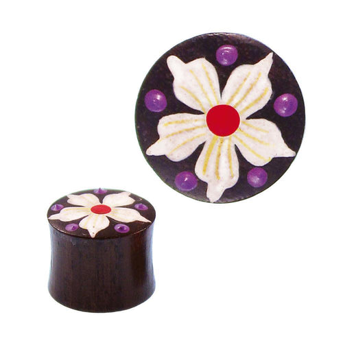 The Holz Plug braun features a round, dark brown design with a hand-painted white flower with a red center and five petals, accented by purple dots. The Tribal tunnel expander is shown from the side and above.