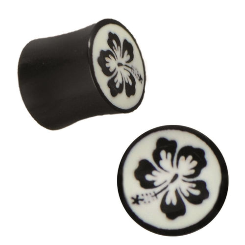 The Plug Horn weiße Gravur schwarze Hawaii Blume handgeschnitzt schwarz Piercing is a black ear plug with a white engraved hibiscus flower, shown from side and top views. A stylish, handcrafted accessory for any piercing collection.