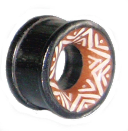 The Holz Tunnel Bone Inlay Stern Sonoholz Tamarindenholz Tribal Plug is a hand-carved black circular expander with a hollow center, featuring a brown tamarind wood face and bold white geometric inlay for unique unisex style.